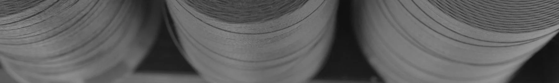 Gros plan de grands rouleaux de papier ou de carton empilés verticalement, montrant une texture en couches.