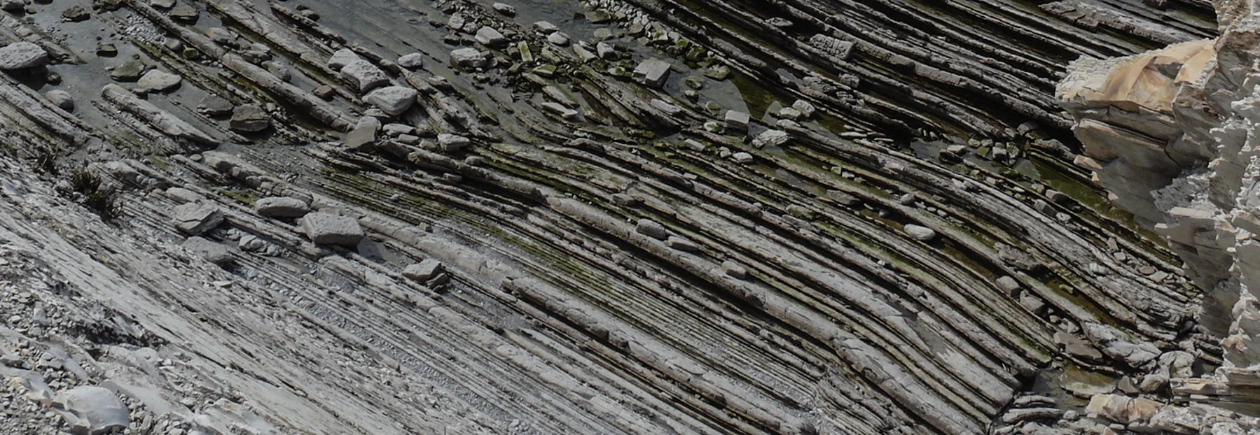 Formations rocheuses avec des motifs sédimentaires stratifiés et des pierres dispersées.