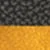 Gros plan d'une surface texturée avec une moitié supérieure noire mouchetée et une moitié inférieure rugueuse jaune doré.