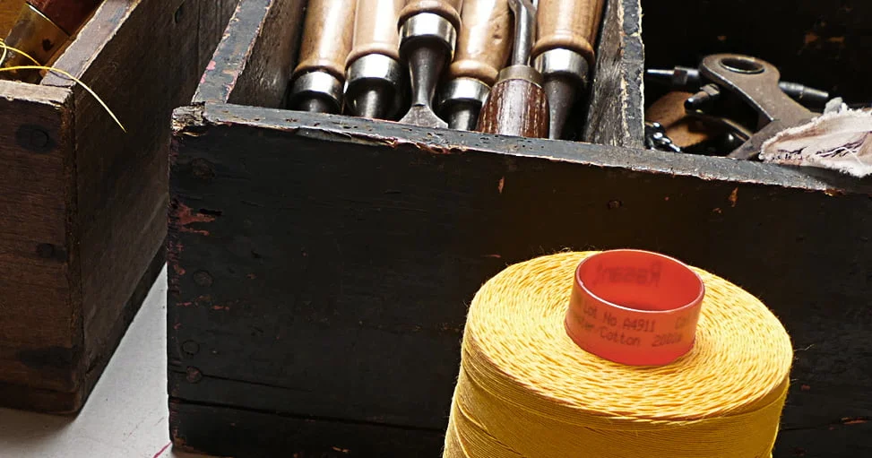 Bobine de fil jaune à côté d'une boîte en bois contenant divers outils.