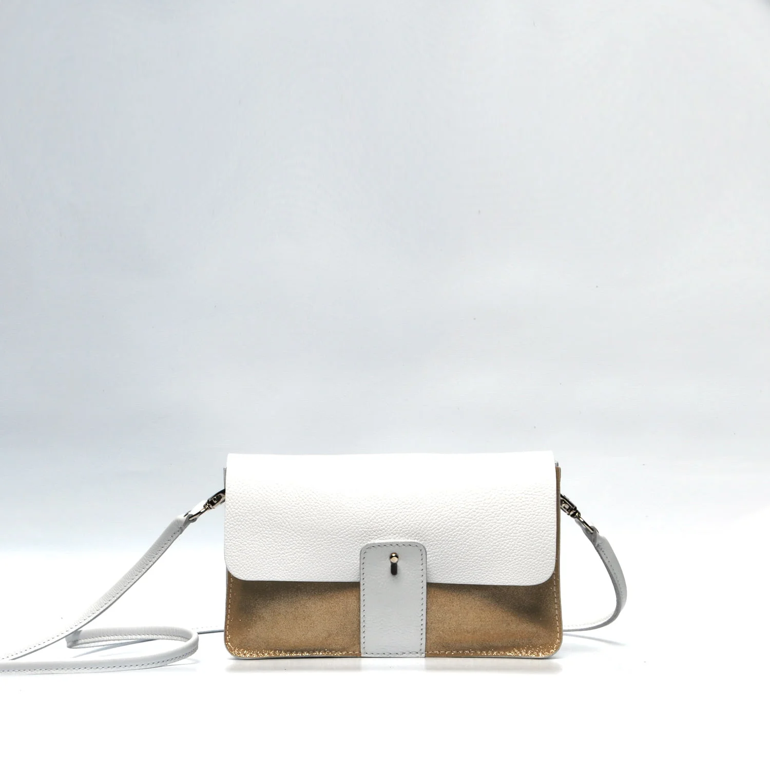 Un petit sac à main structuré avec un rabat blanc, un corps beige et une fine bandoulière, sur un fond uni.