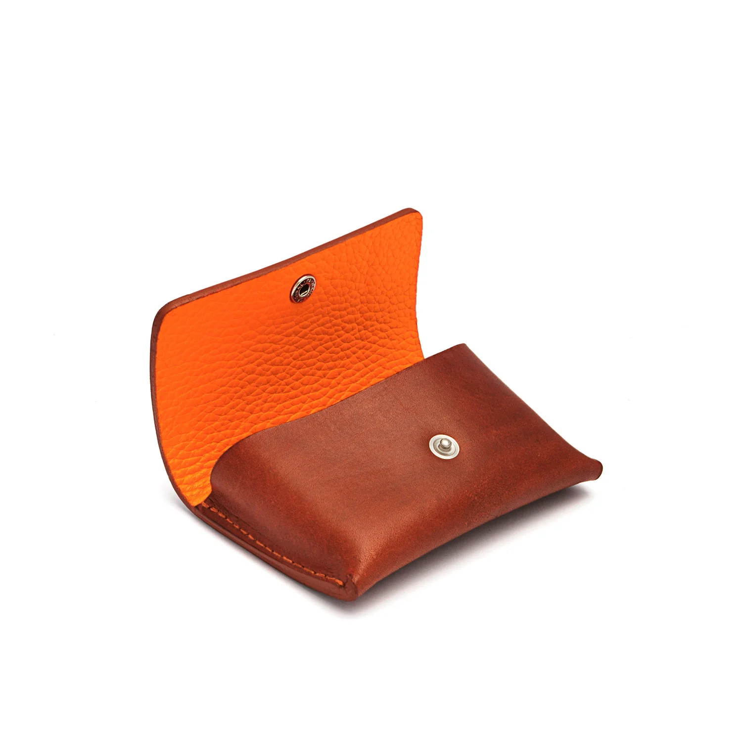 Pochette à monnaie en cuir marron avec un rabat ouvert, révélant un intérieur orange et une fermeture à bouton-pression.