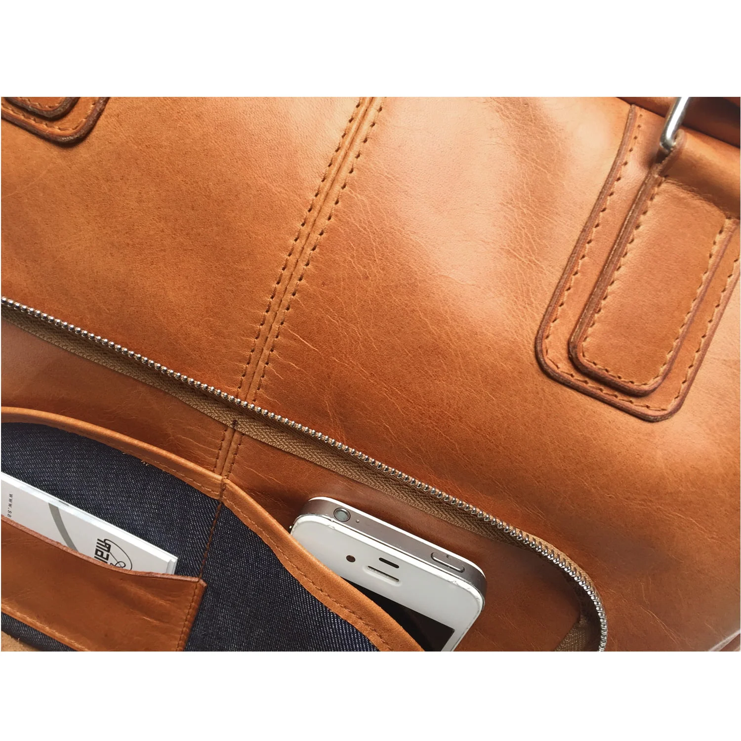 Un sac en cuir avec des poches avant visibles, contenant un smartphone et une carte.