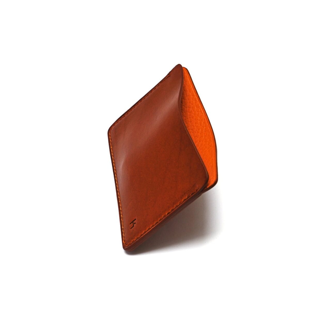 Portefeuille en cuir marron au design minimaliste, légèrement ouvert pour révéler un intérieur orange, sur fond blanc.