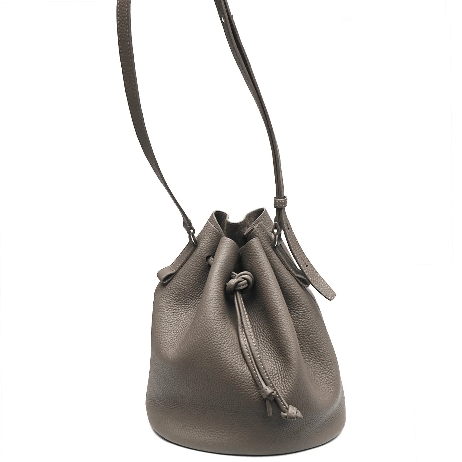 Un sac seau en cuir gris avec cordon de serrage, une bandoulière réglable et une fermeture à nœud.