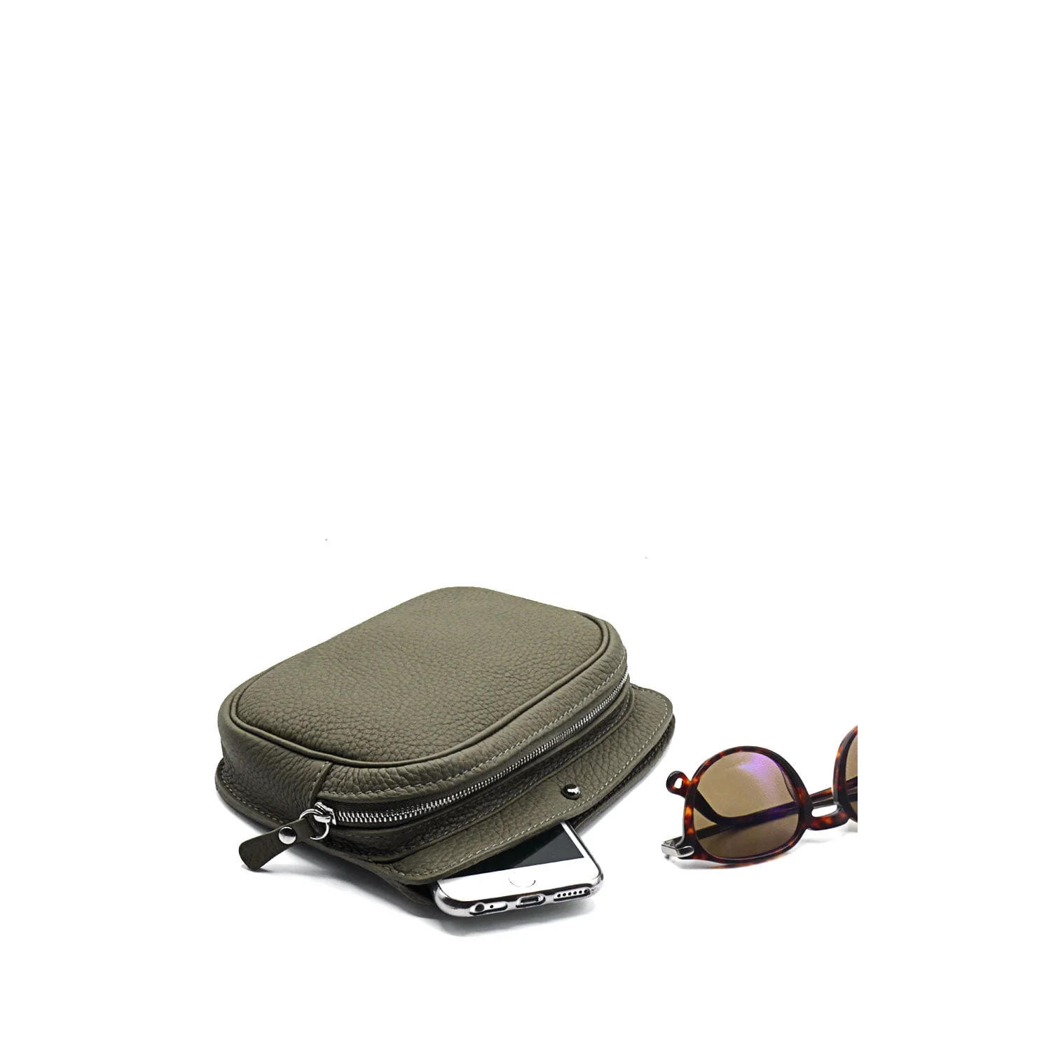 Une pochette zippée taupe contenant partiellement un smartphone est placée à côté de lunettes de soleil rondes marron aux verres teintés sur fond blanc.