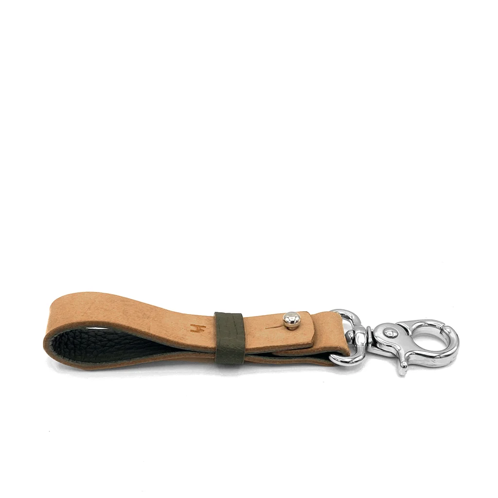 Porte-clés en cuir avec fermoir en métal et accent vert sur fond blanc.
