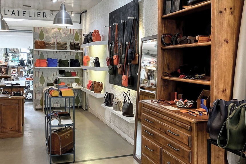 L'intérieur d'un magasin de détail présente des étagères et des présentoirs avec divers sacs à main et accessoires colorés. Des meubles en bois complètent le design épuré et moderne.