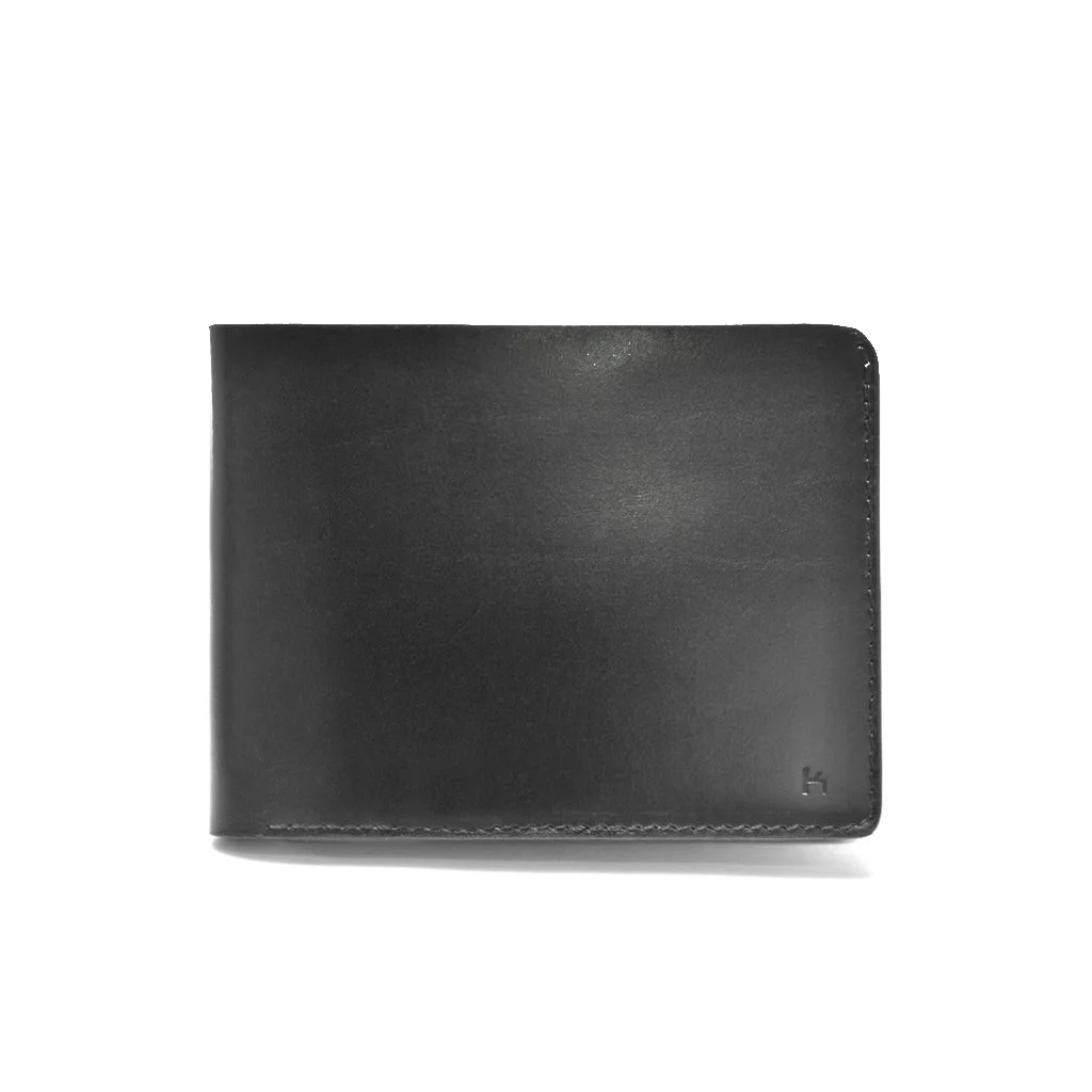Un portefeuille en cuir noir avec des coutures minimales, fermé et placé à la verticale sur un fond blanc.