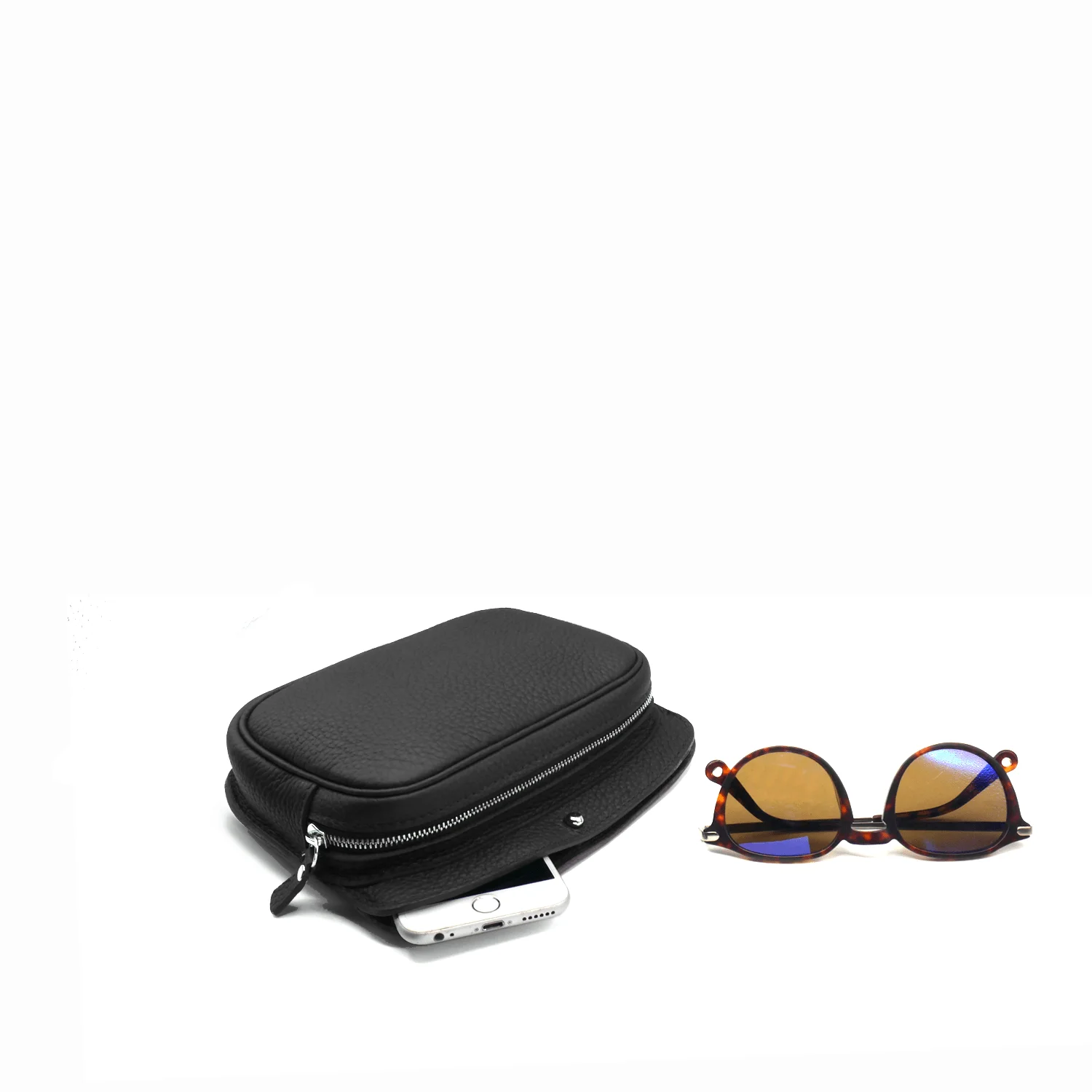 Une pochette noire zippée avec un smartphone partiellement visible et une paire de lunettes de soleil en écaille de tortue à côté.