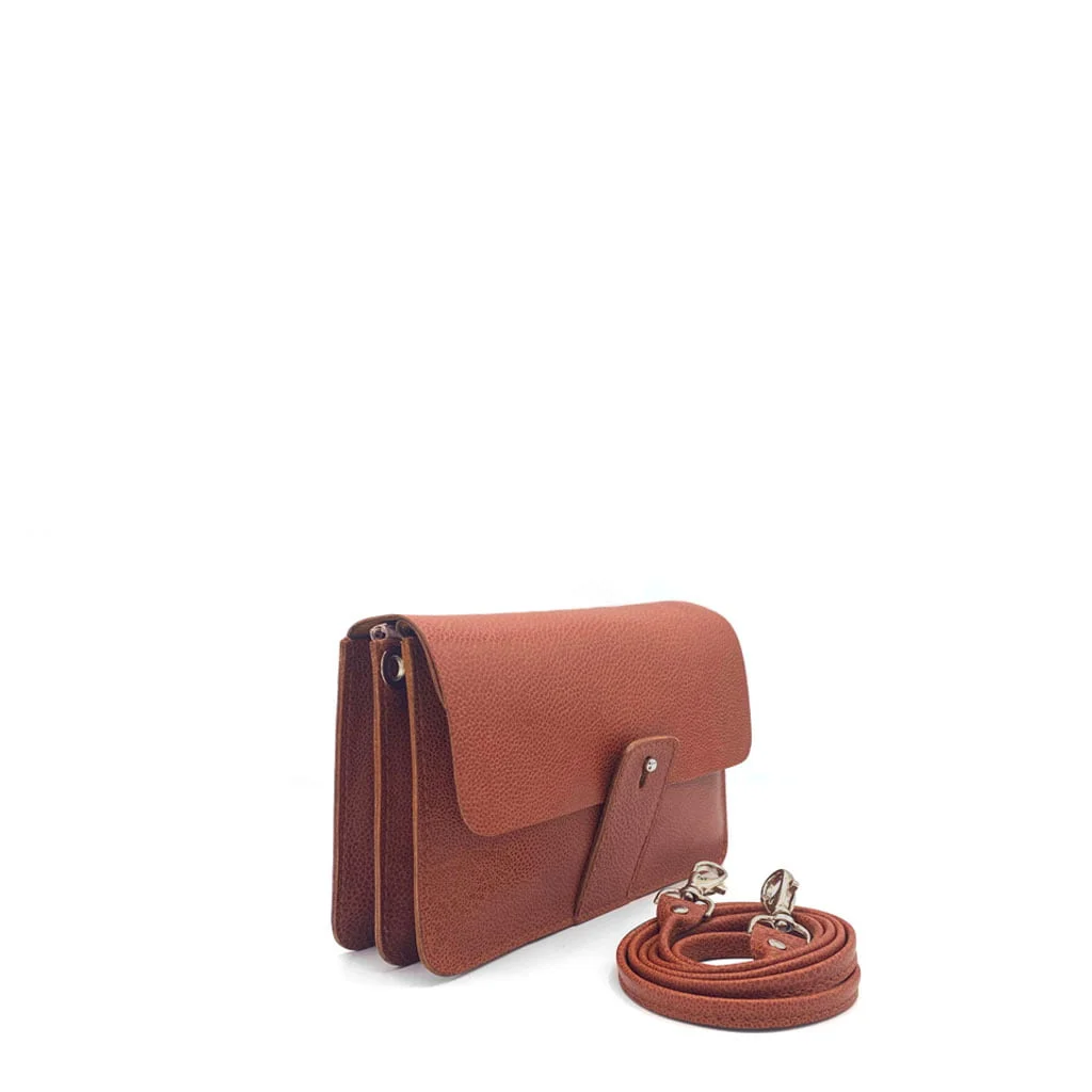 Sac à main en cuir marron avec fermeture à rabat et bandoulière amovible, placé sur un fond blanc uni.