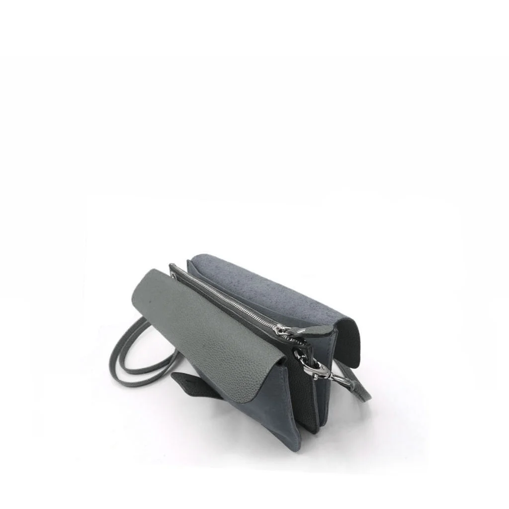 Un petit sac à main gris minimaliste au design épuré et doté d'une bandoulière, posé sur un fond blanc.