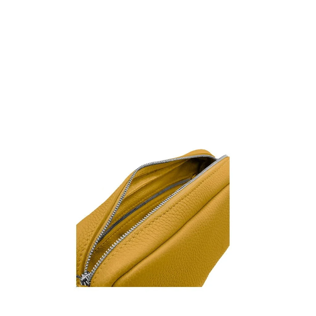Gros plan d'un sac en cuir jaune avec une fermeture éclair argentée partiellement ouverte, montrant l'intérieur.