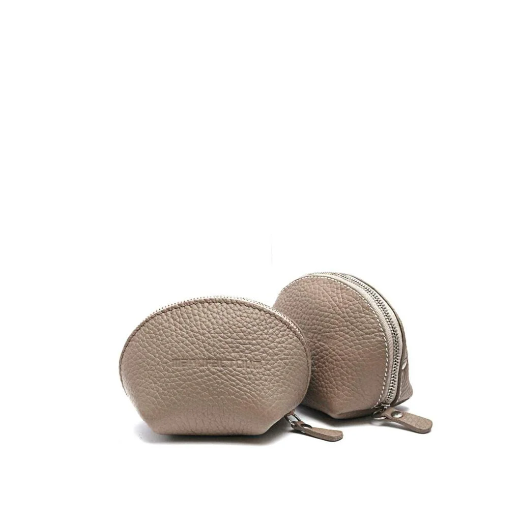 Deux petits porte-monnaie ronds en cuir beige avec fermetures éclair sur fond blanc uni.
