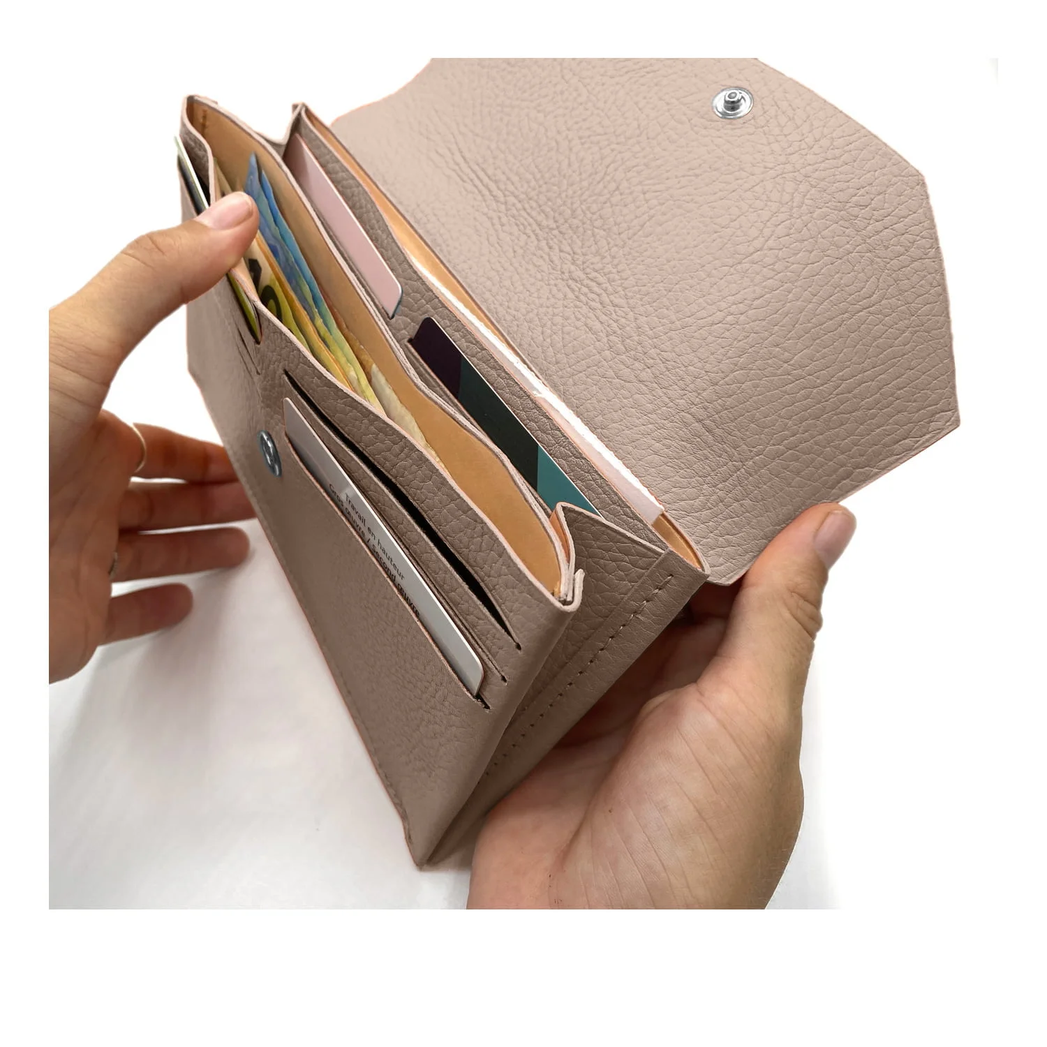 Mains tenant un portefeuille beige ouvert contenant des cartes et de la monnaie.
