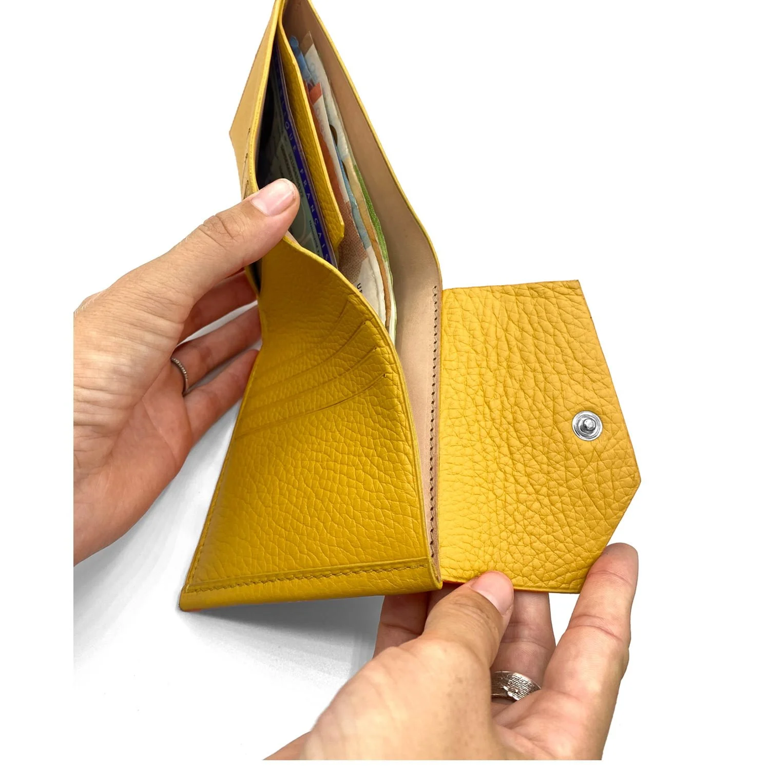 Deux mains tiennent un portefeuille en cuir jaune ouvert, révélant plusieurs cartes et de l'argent plié à l'intérieur.