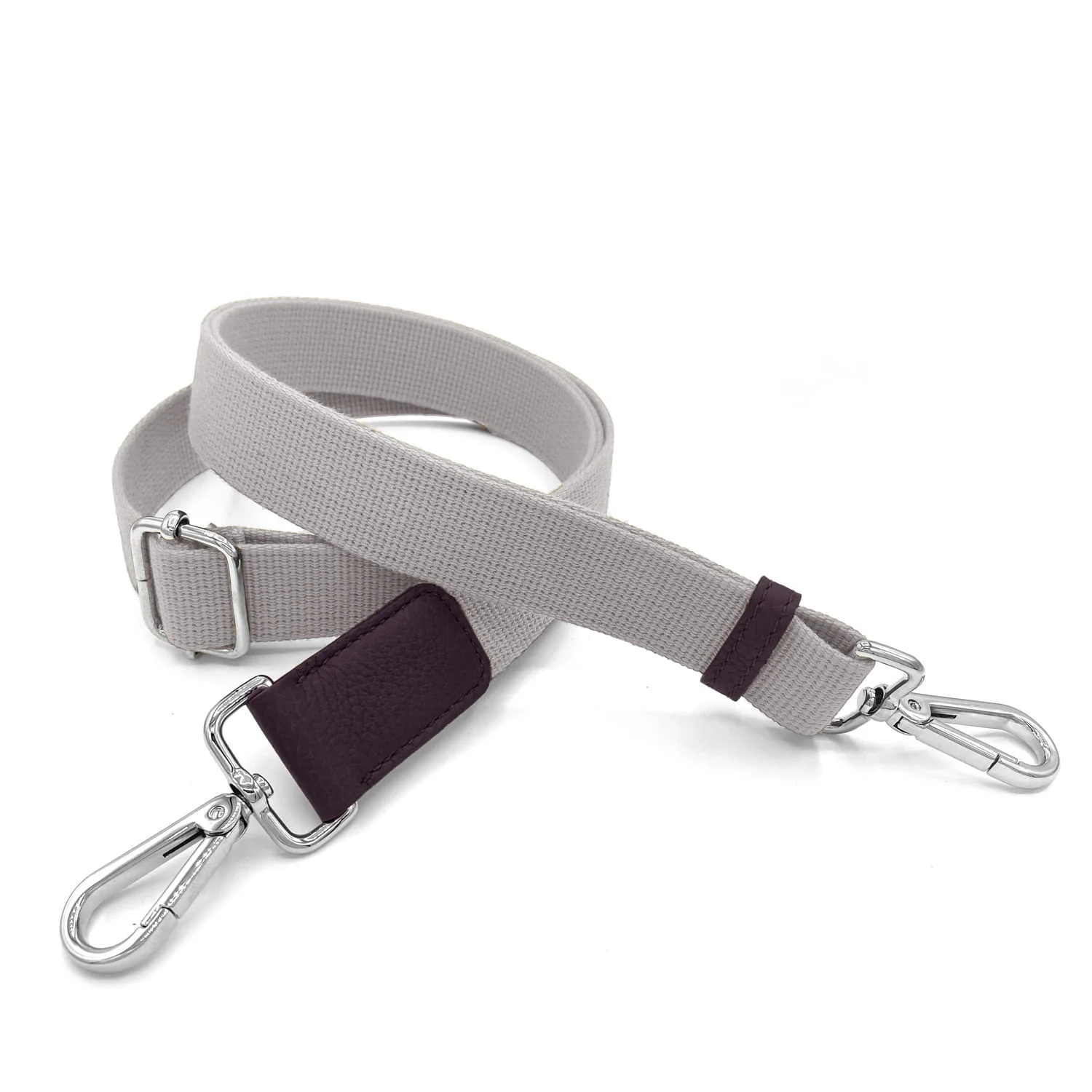 Une sangle réglable grise avec des clips métalliques aux deux extrémités est enroulée sur un fond blanc.
