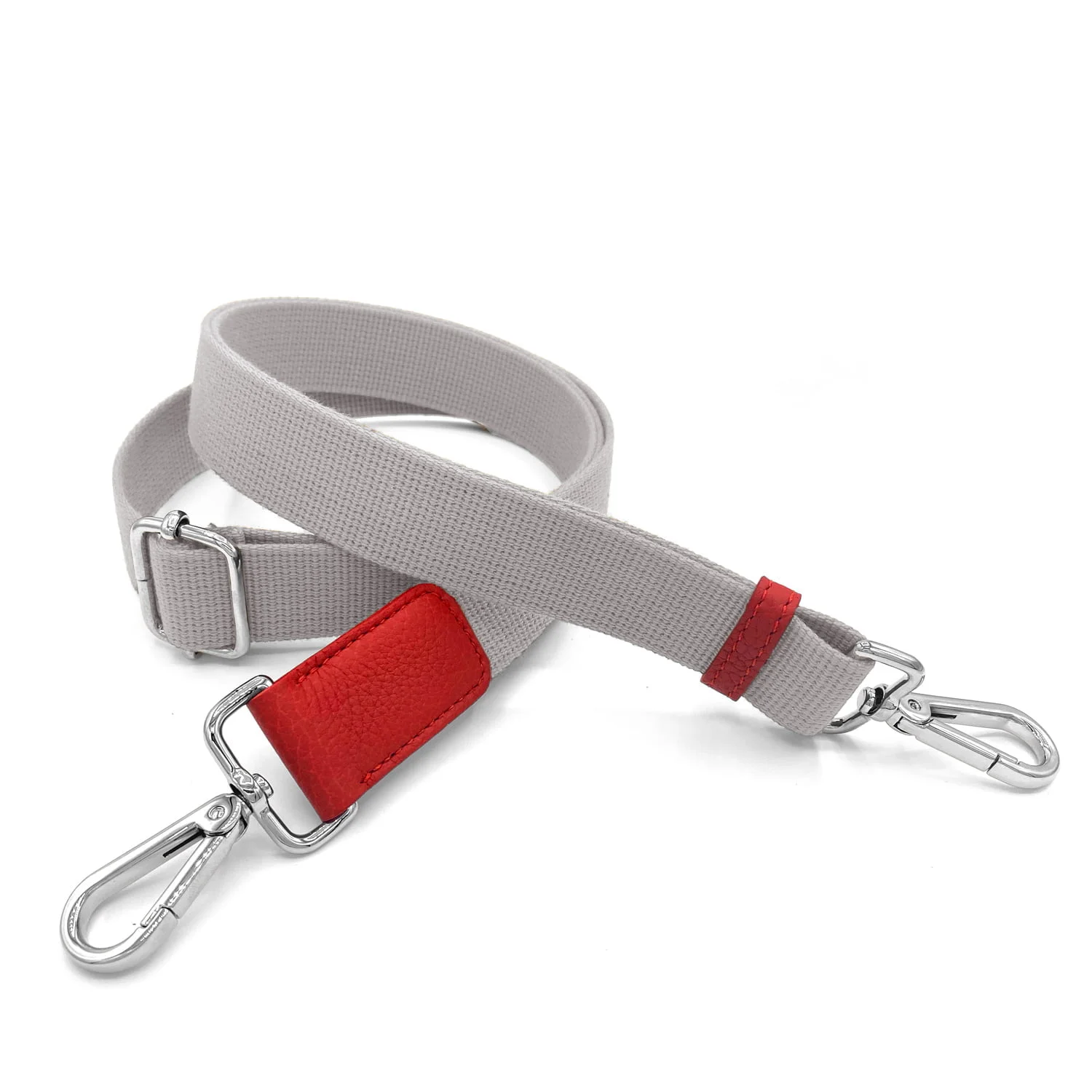 Un bracelet gris avec des fermoirs en métal argenté et un patch en cuir rouge enroulé sur une surface blanche.