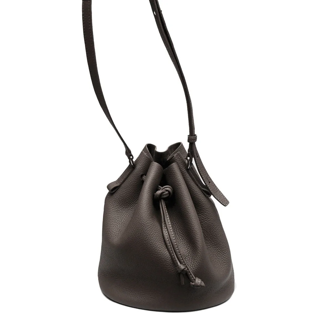 Sac seau en cuir marron foncé avec fermeture à cordon et longue bandoulière.