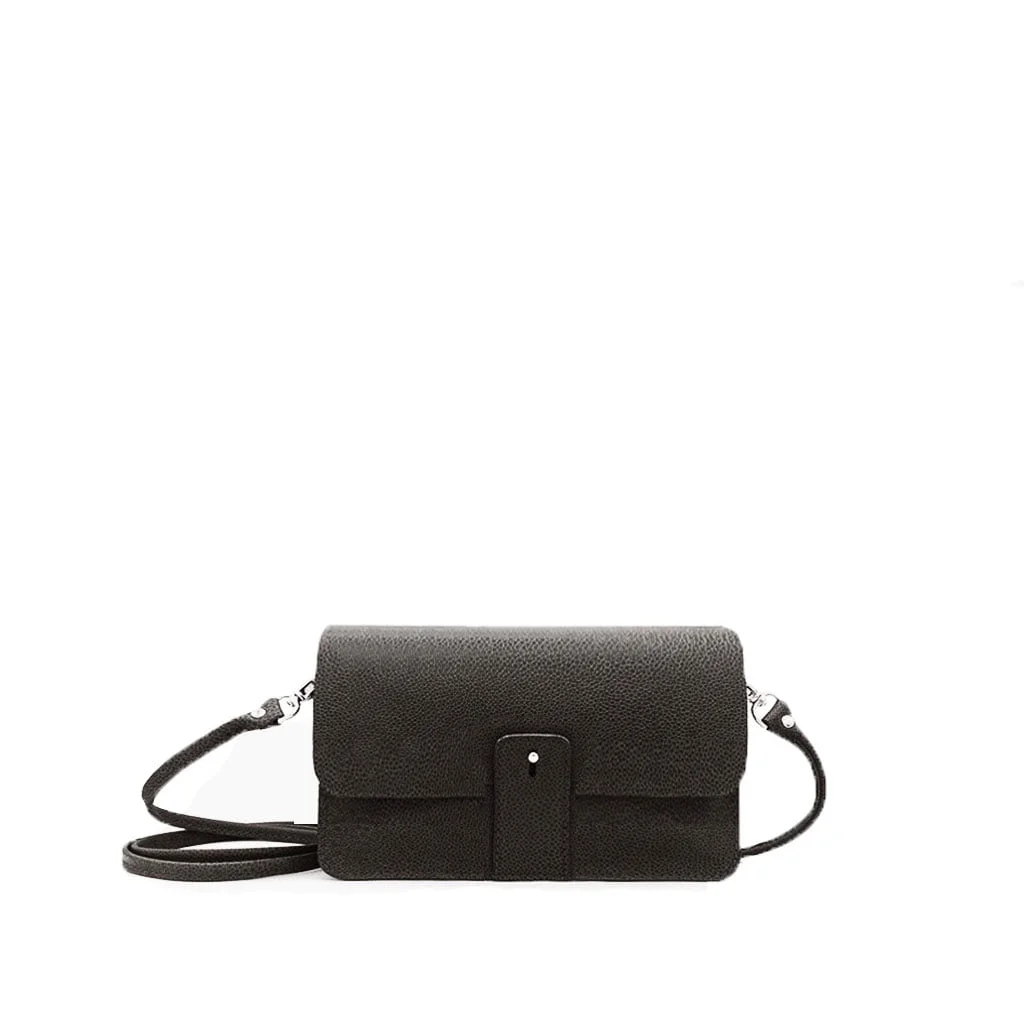 Un petit sac bandoulière en cuir noir avec un rabat avant et une fine bandoulière, placé sur un fond blanc uni.