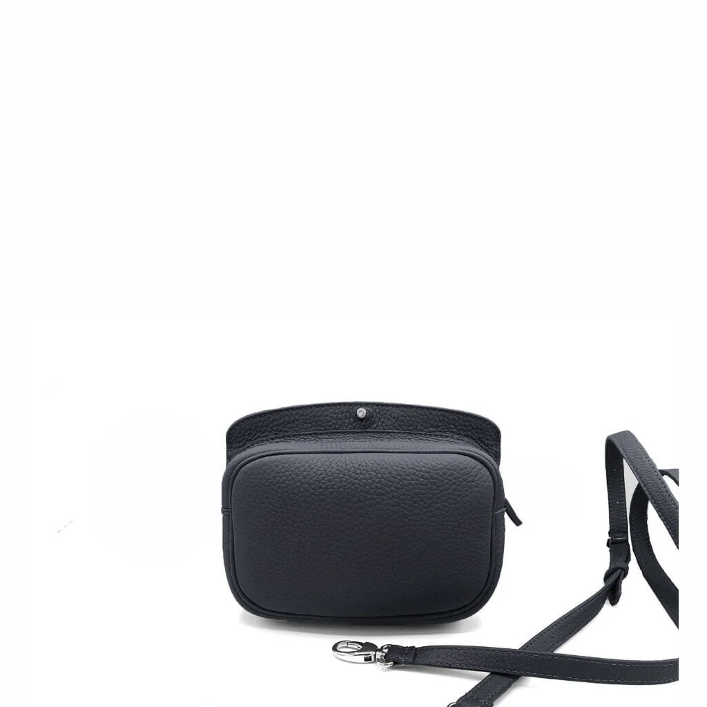 Un sac à bandoulière en cuir noir avec une fermeture à rabat et une bandoulière amovible repose sur une surface blanche.