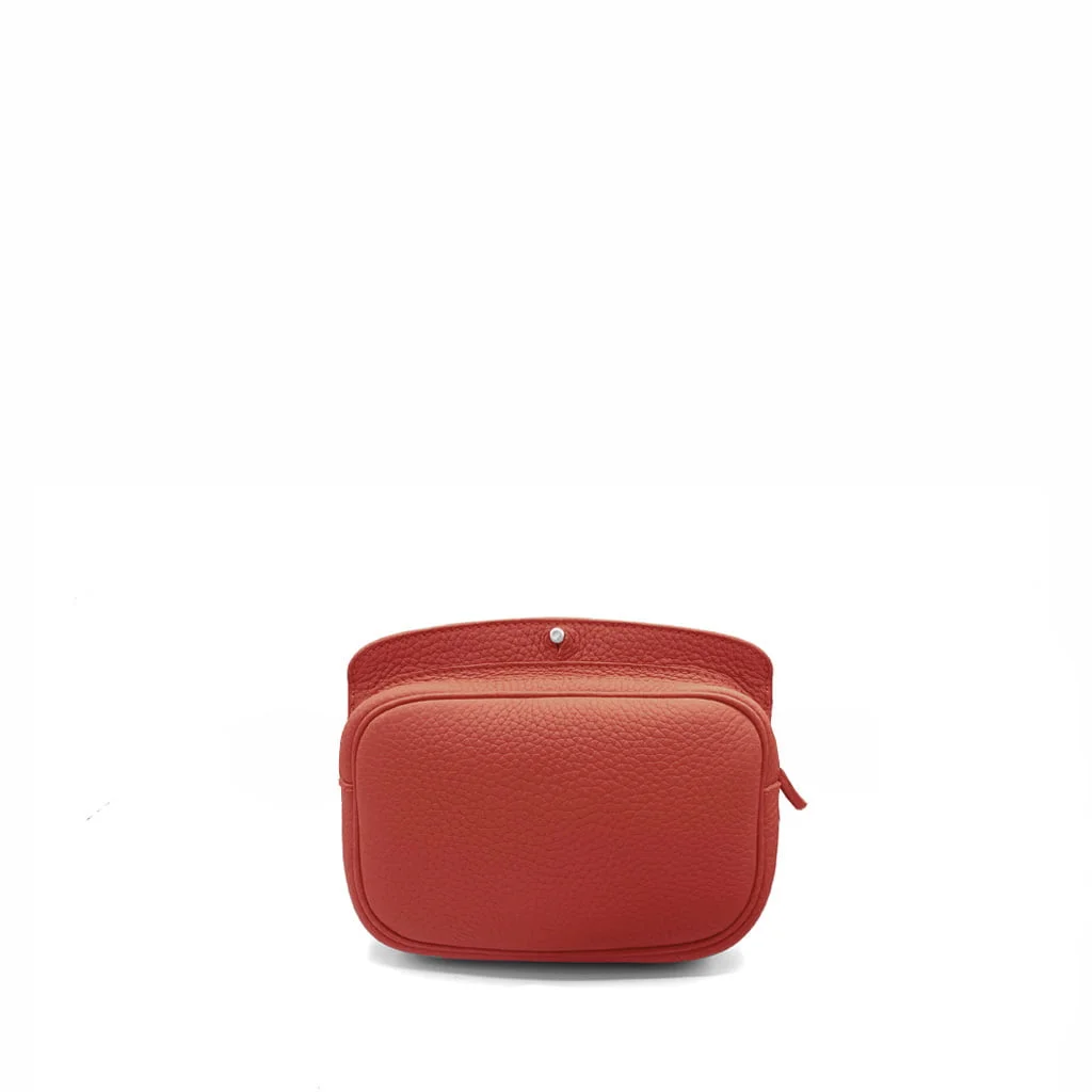 Un petit sac en cuir rouge avec une poche avant et une fermeture zippée, présenté sur un fond blanc.