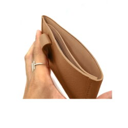 Main tenant un portefeuille en cuir marron ouvert avec une fente pour carte intérieure visible.