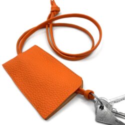 Un porte-cartes en cuir orange attaché à un cordon avec un jeu de clés.