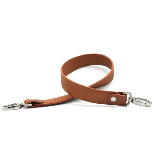 Gros plan d'un bracelet en cuir marron avec des fermoirs argentés à chaque extrémité.