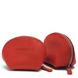 Deux petites pochettes à fermeture éclair en cuir texturé rouge sont présentées côte à côte, l'une tournée vers l'avant et l'autre montrant son côté et sa fermeture éclair.