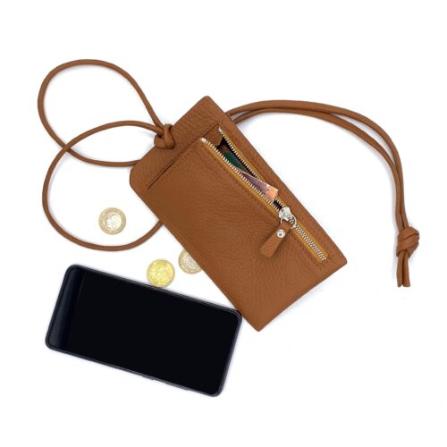 Une pochette en cuir marron avec une fermeture éclair et une sangle, contenant de l'argent liquide et des pièces de monnaie, est placée à côté d'un smartphone et de plusieurs pièces de monnaie sur un fond blanc.