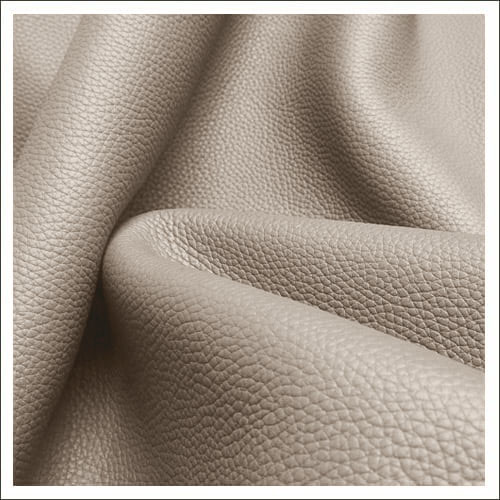 Gros plan sur une matière en cuir texturé beige pliée, dont la fleur est visible et qui présente des plis naturels.